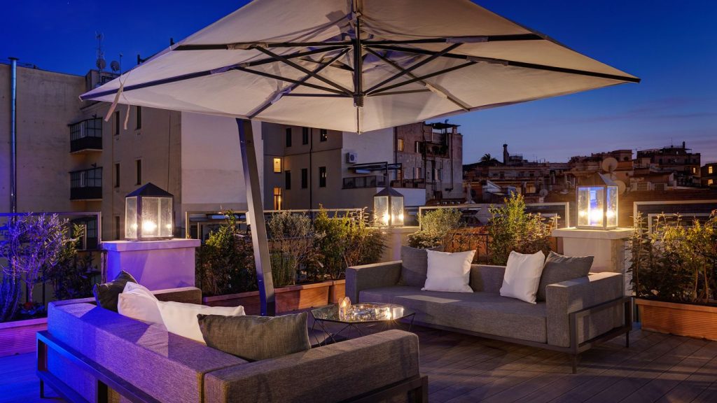 Terrassa rooftop d'un hotel de luxe al capvespre amb sofàs i il·luminació elegant per al servei de còctels de Quicktail.